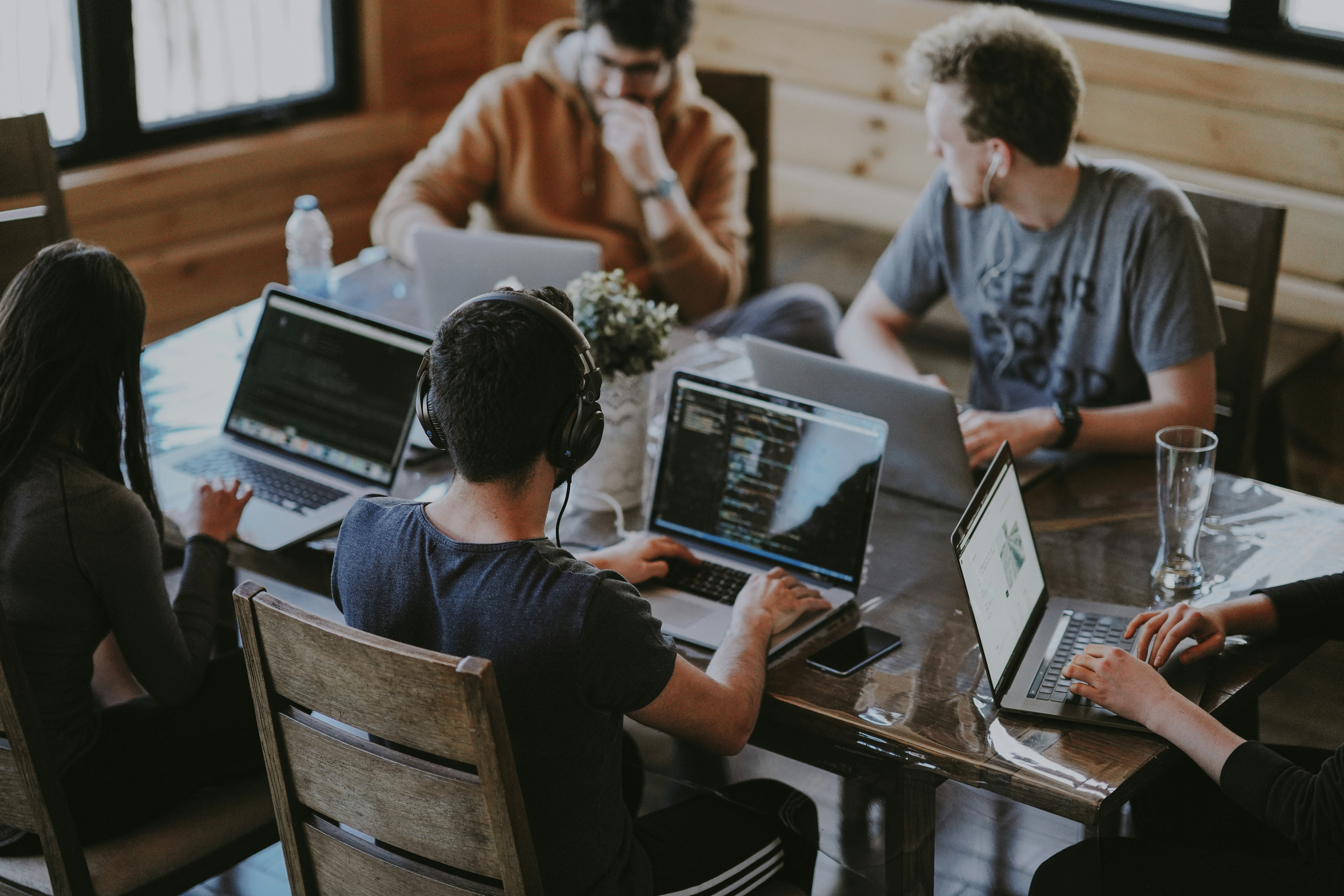 Five coders working around a table with laptops open.
